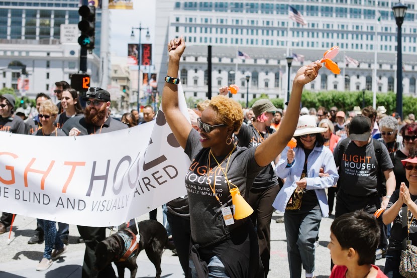 A woman cheers in front of a LightHouse banner