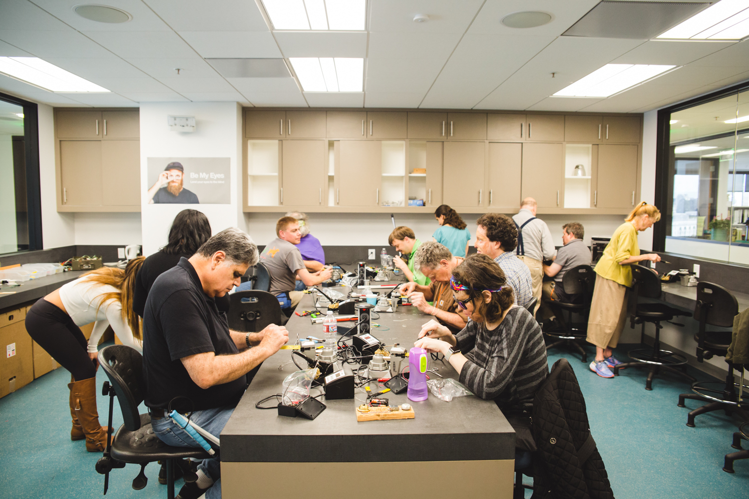 A group of 13 students, instructors, and volunteers are hard at work around the long central table in LightHouse’s Innovation Lab. 