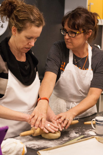 Sydney Ferrario shows student, Jane Fowler, how to knead dough.