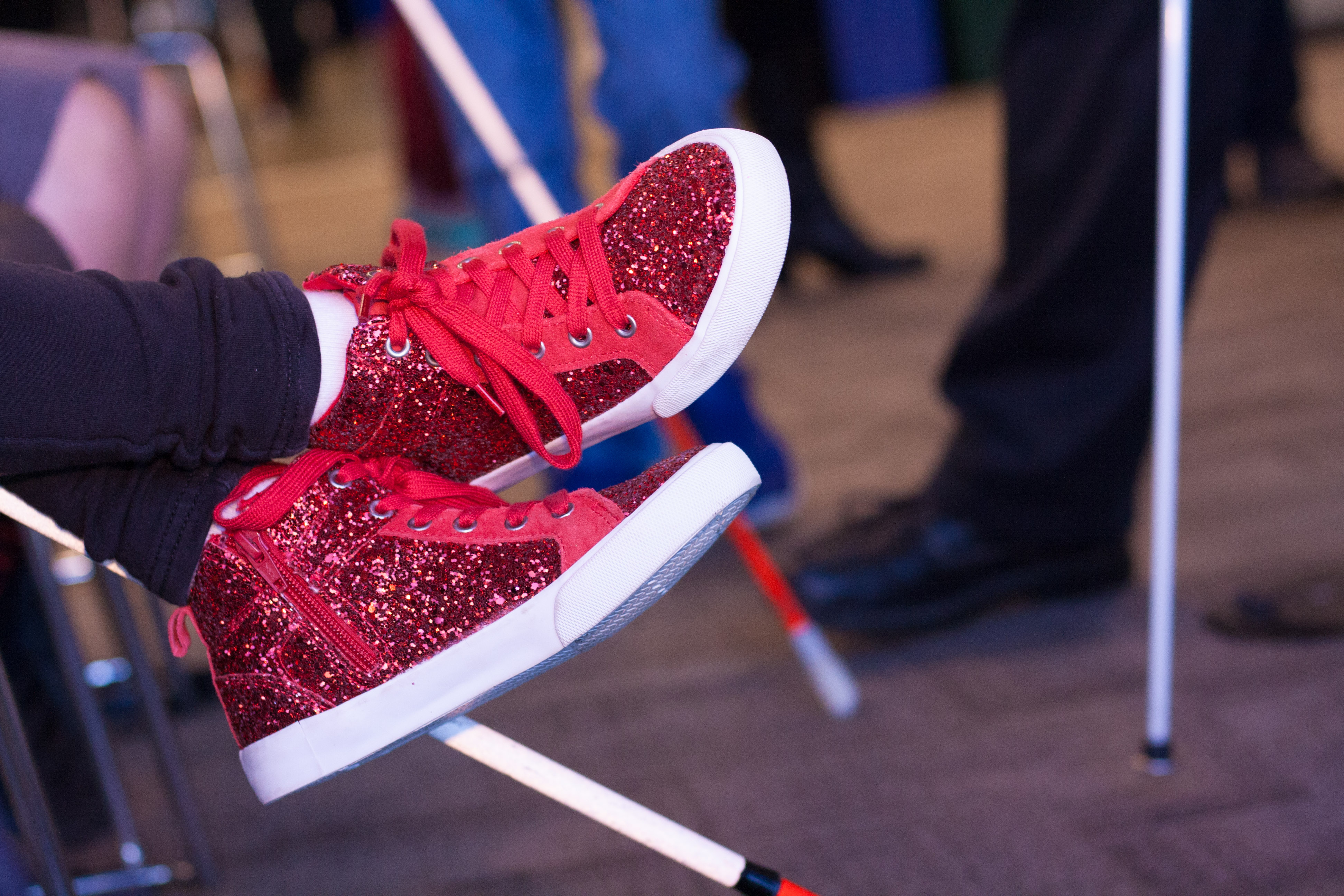 A closeup of a student's festive and sparkly red high-tops, with canes visible in the background.