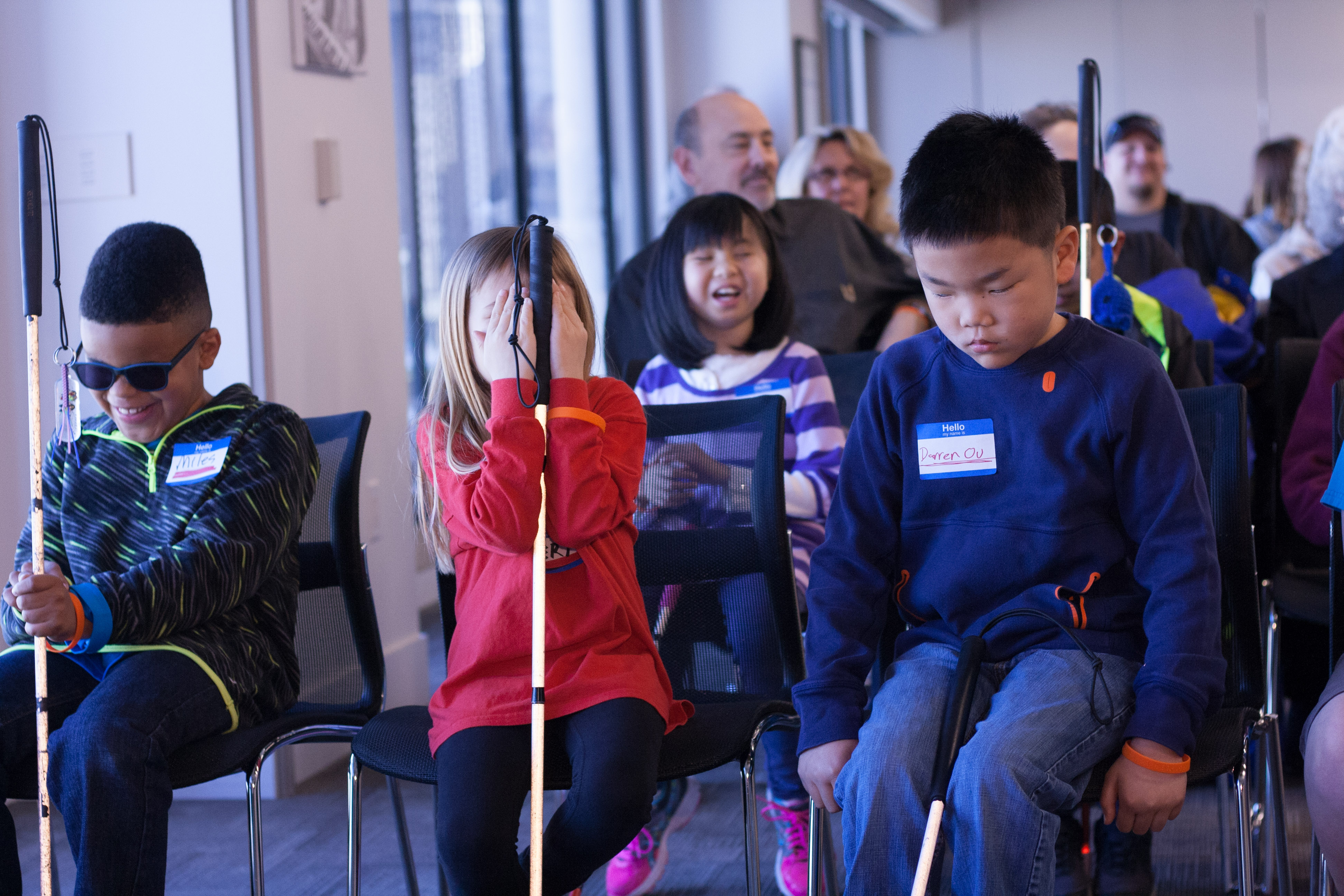 A shot of the audience shows the kids laughing and one competitor playfully covering her face.