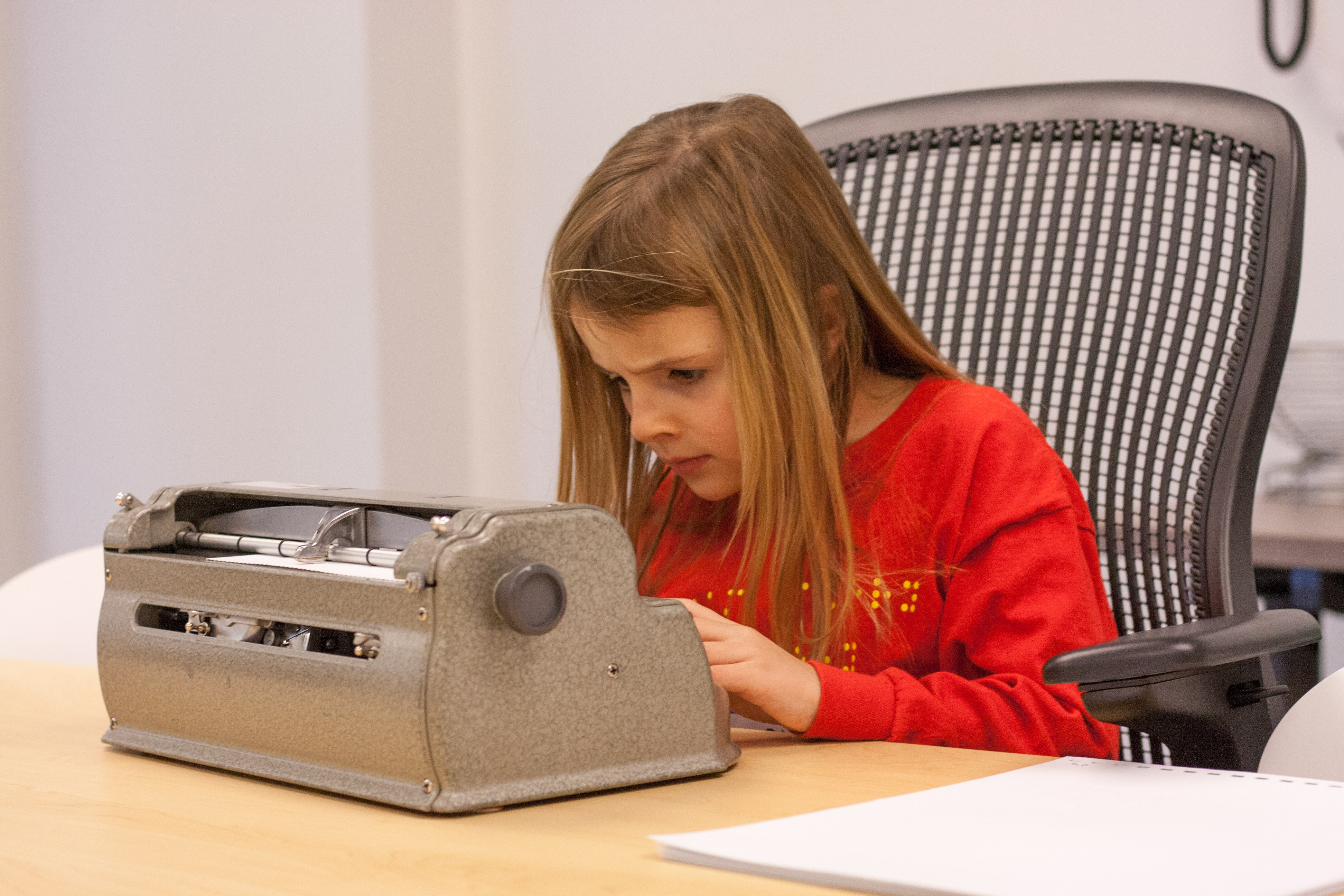 Apprentice competitor Avery leans closer to her brailler and furrows her brow intently.