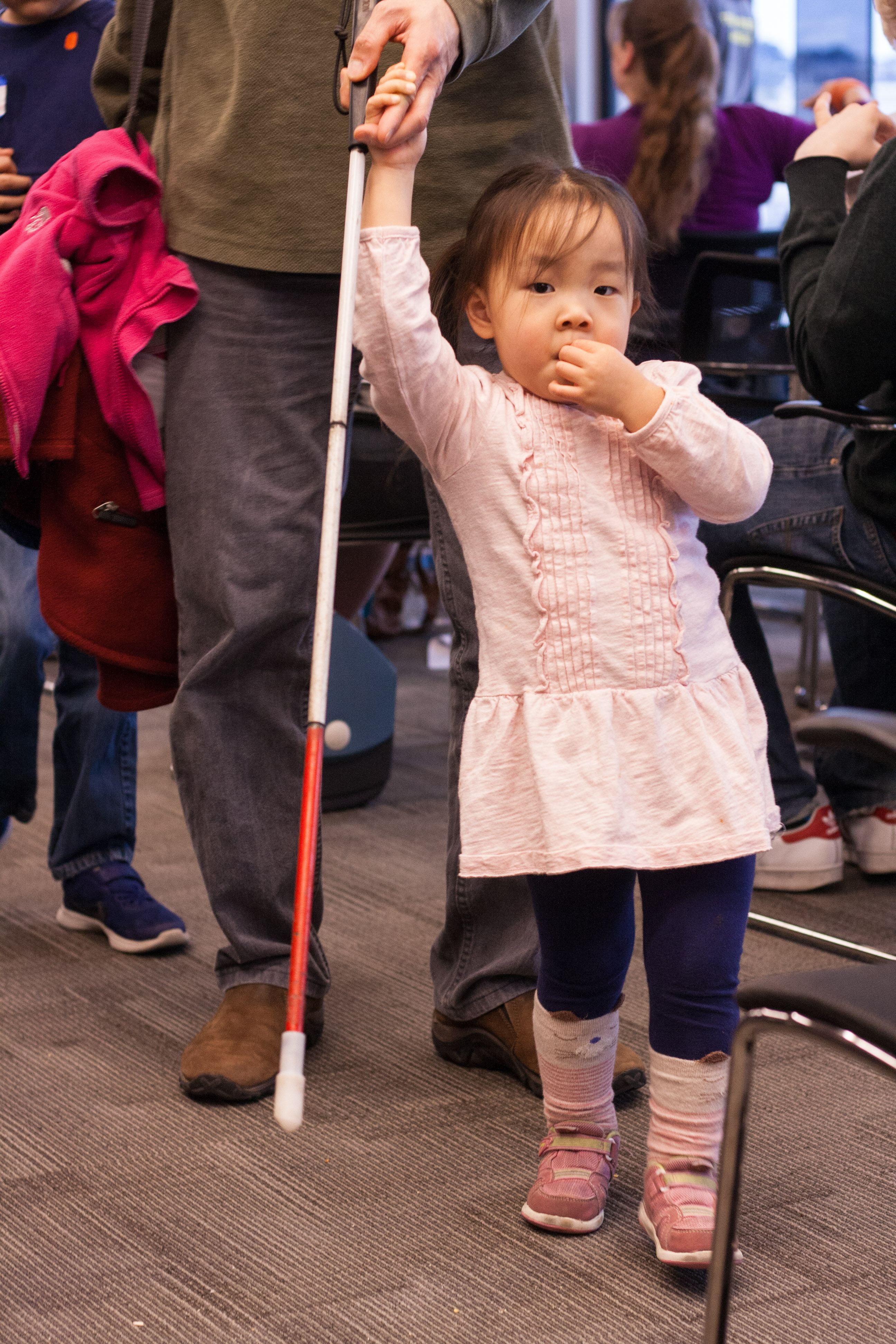 A competitor's little sister walks holding her dad's hand.