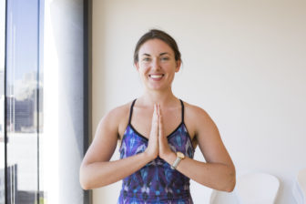 Meagan smiles while putting her hands together in namaste.