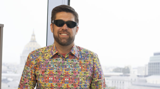 A smiling Toby wears a multi-colored shirt.