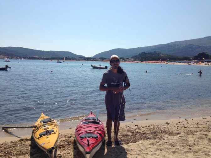 Ahmet stands on the beach next to his kayak