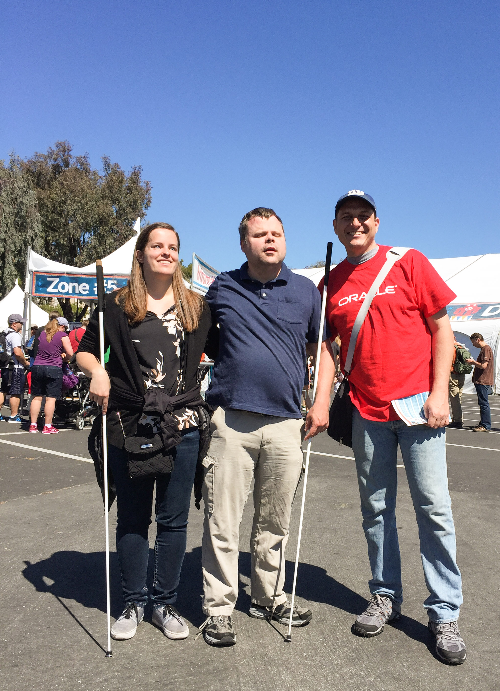 Two students and an Oracle volunteer pose together.
