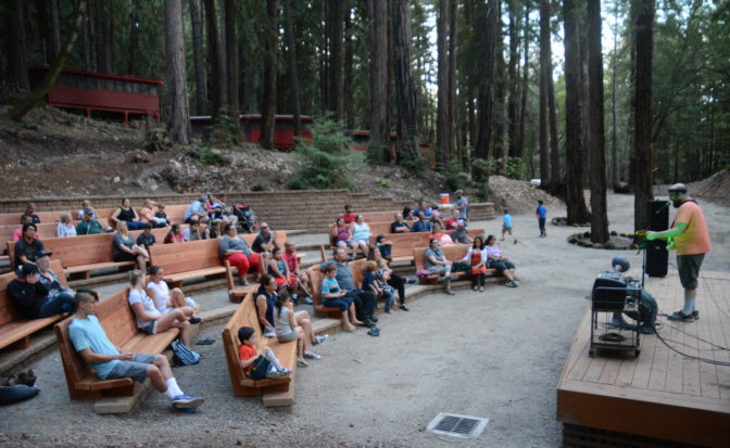 A side view of a crowd listening to music in the Redwood Grove Theater.