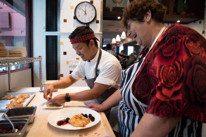 Penny laughs in the One Market Restaurant kitchen with pastry chef Mac while plating a peach galette.