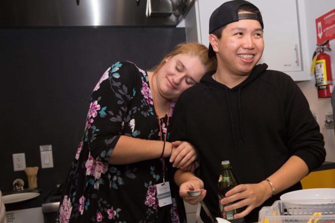 Sarah leans against Chester laughing, while the two friends work on a meal for the Mentor Appreciation dinner.