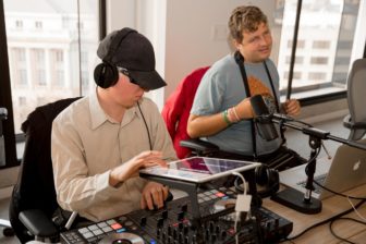 At left, Blind DJ Ryan Dour performs a set using an iPad and DJ equipment, while Audio Academy student Daniel listens with delight at right.