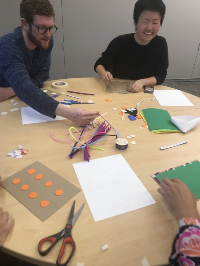 Designers sit around the table discussing their designs during the planning phase. Some of the conversations asked this question: What is the most useful information to include for blind map readers?