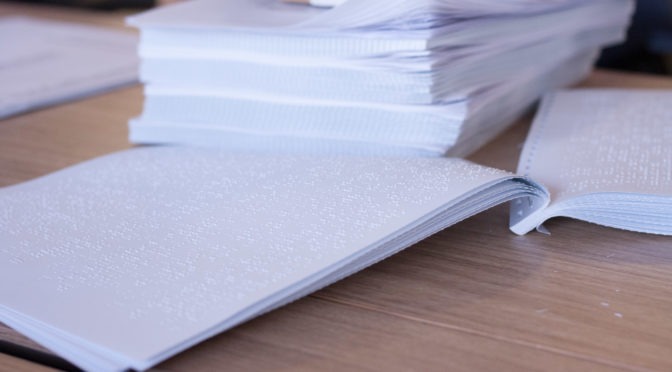 Paquete de papel braille y un primer plano de un documento Braille