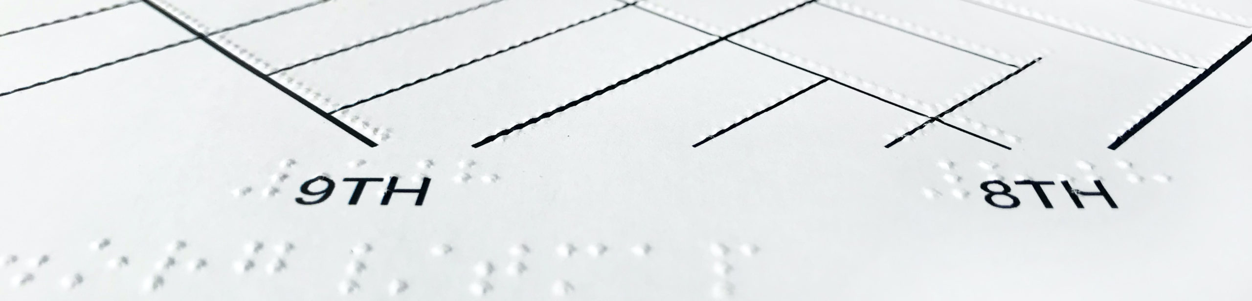 detail of tactile map showing embossed street lines over black ink lines, braille and print labels for 8th and 9th streets.
