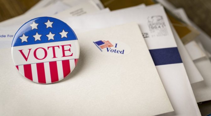 A vote pin, "I Voted" sticker and ballots.