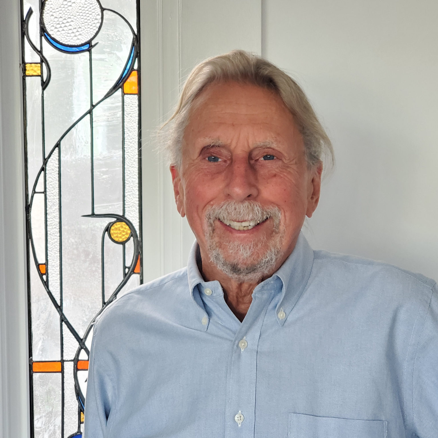 Jerry Kuns stands beside a stained glass window