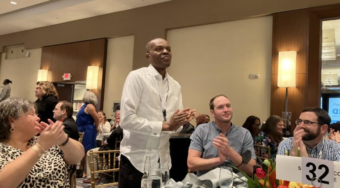 Dr. Charles Umo stands at a table at the 2022 NIB Conference