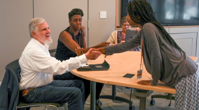 LightHouse staffer Bobbi Pompey observes a student shaking hands with LightHouse mentor Mike Cole