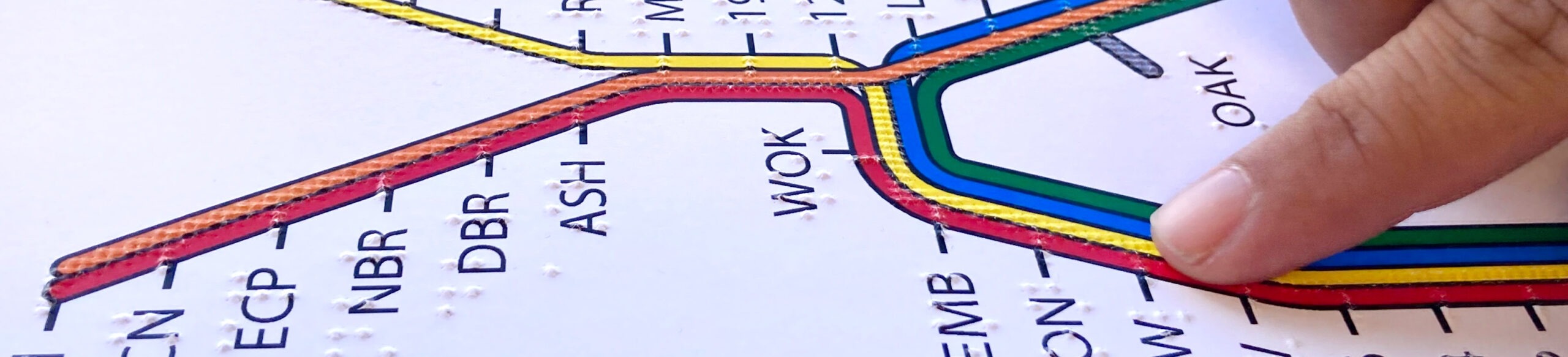 A finger explores a tactile BART system map.