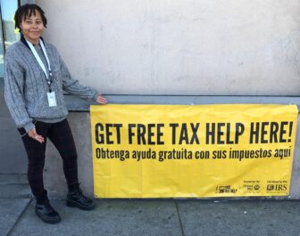 A person holding a sign that reads get your free tax help here!