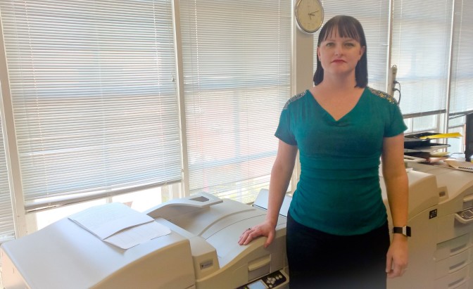 BJ Epstein stands next to a braille printer
