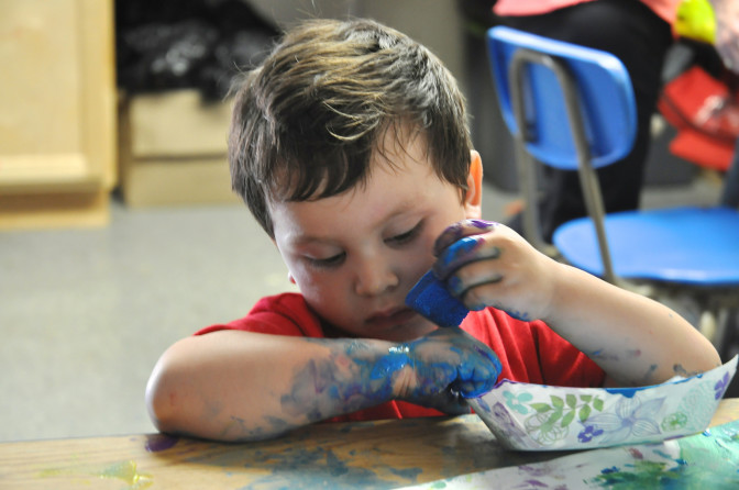 little boy is not afraid to get messy when it comes to fingerpainting