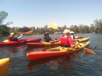 Kids in kayaks – three kayaks slice through calm waters during a Youth Program outing
