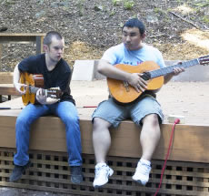 Travis Nichols (left) and Jimmy Cong play guitar while sitting on the newly built Redwood Grove Stage