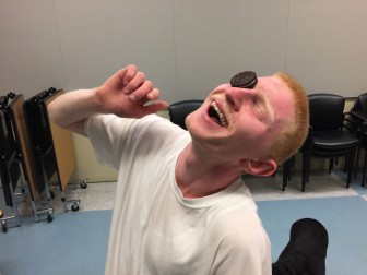 Mentor Nasir, with a big grin on his face, practices how to roll an Oreo cookie from the forehead to the mouth without using ones hands.