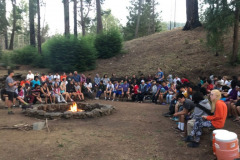 Teens who are blind or have low vision sit around the fire circle at Enchanted Hills Camp in 2019.