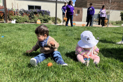 Two Little Learners sit side by side on the grass