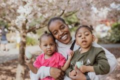 Mom poses with her two children, one is holding shaker noise making eggs